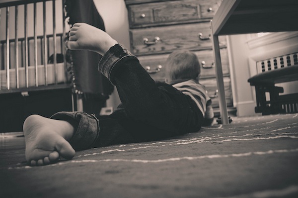 little boy laying on the floor in his room playing 