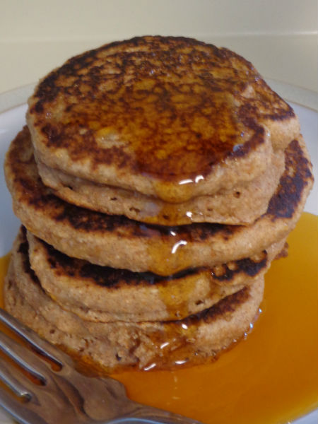 stack of four cinnamon applesauce pancakes covered in maple syrup