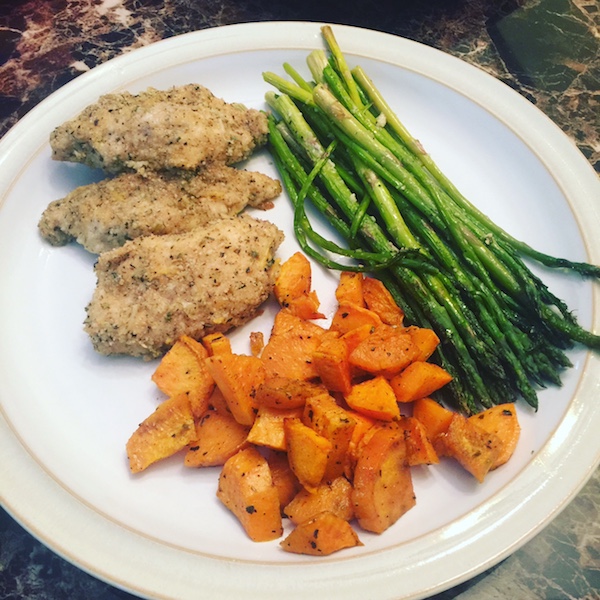 white plate topped with oven roasted sweet potatoes, asparagus and 3 pieces of oven fried chicken