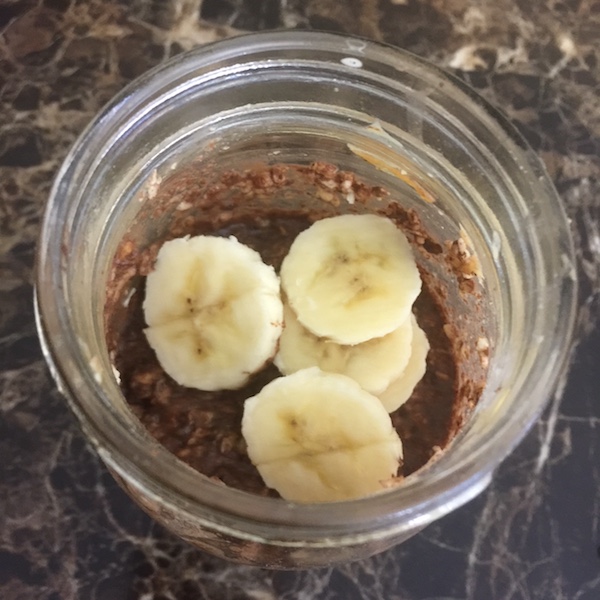 mason jar with chocolate peanut butter overnight oats topped with sliced bananas