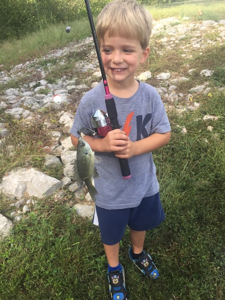 Dalton holding fishing rod and a fish he caught