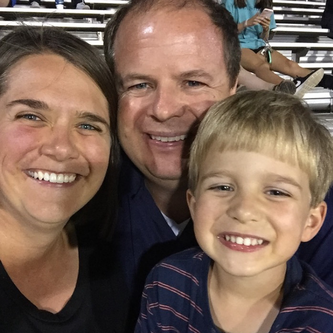 family sitting in stands at a football game