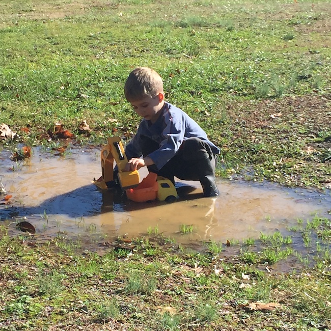 little boy playing in mud puddle