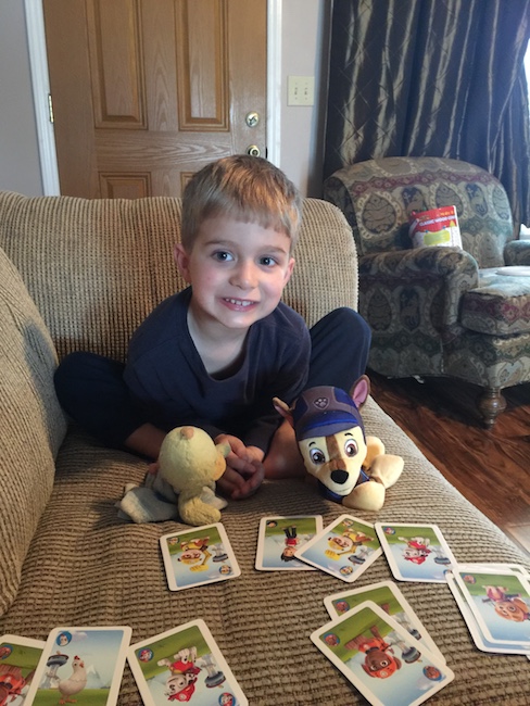 little boy with stuffed animals playing cards 